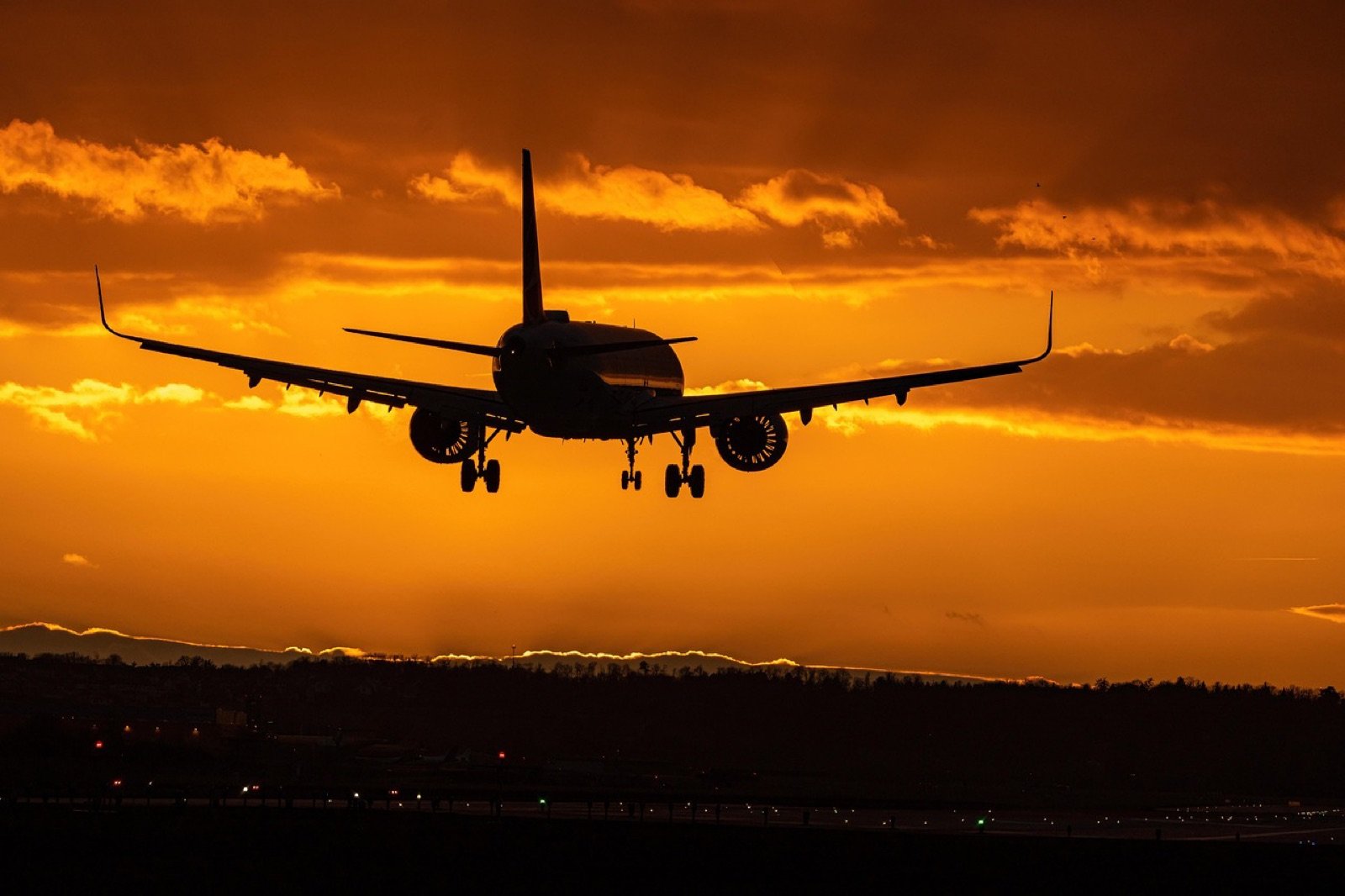 A plane coming in against an orange sunset