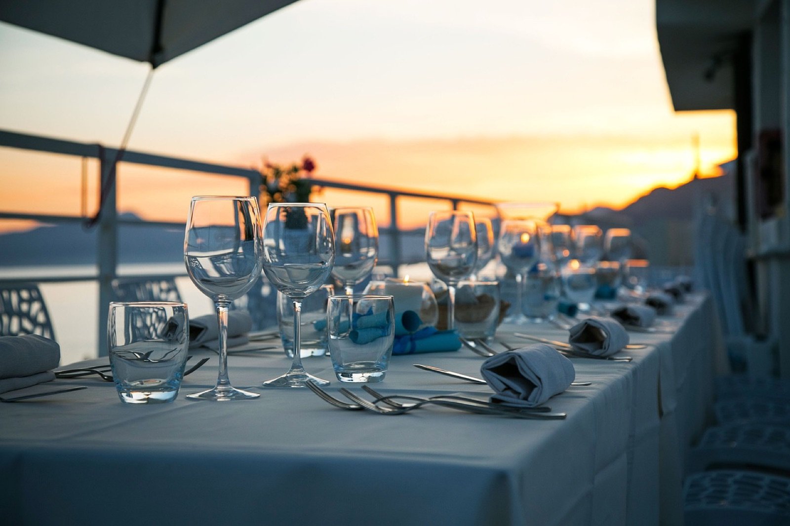 A long table set for dinner by the sea at sunset